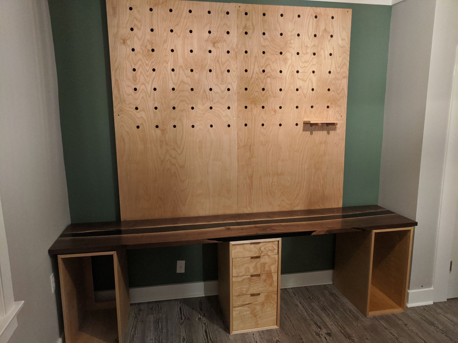 Built in computer desk for 2 people with custom peg board shelving backsplash, and walnut and black resin river pour desktop